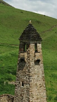 Aerial around view of medieval tower complex in the mountains of Ingushetia, Russia. Vertical video