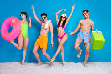 Full length photo of funky positive fellows company wear swimsuits celebrating weekend together isolated blue color background