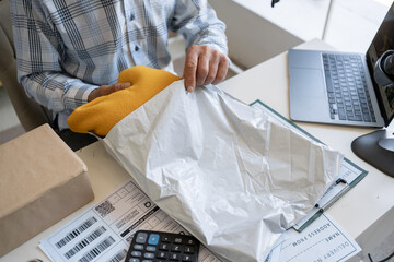 businessman in an online clothing store is packing sweater. Placing buyer's order