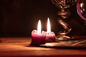 A detailed close-up shot of two lit pink candles with a dark, mystical background, emphasizing a...