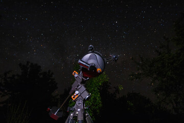 An astronomical telescope is aimed at the night starry sky. An amateur optical telescope stands in...