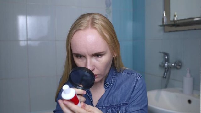 Toothpaste ingredients. Girl checks composition of toothpaste and is surprised by dangerous composition of product. Emulsifiers, preservatives, dyes, PEG, SLS, parabens, diethanolamine