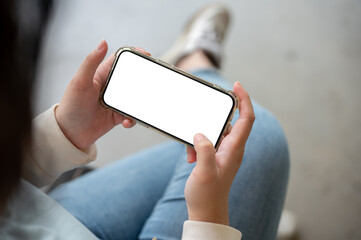 A woman holding a smartphone in a horizontal position, watching a video or playing a mobile game.