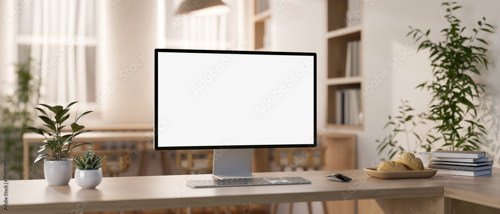 Poster a computer mockup and objects are on a wooden table in a contemporary minimalist co-working space.