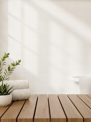 A wooden table features towels and a potted plant against the white wall in a minimalist bathroom.