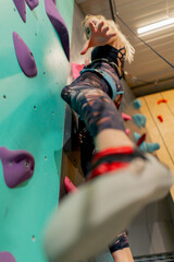 close up the climbing wall young girl climbs the wall for the first time, the coach belays with a safety rope