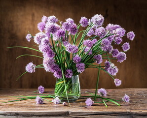 Bouquet of onion (chives) flowers in the vase on the wooden table.