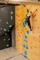 at the climbing wall young girl goes down the safety rope, the coach insures against falling