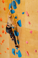 close up at the climbing wall young girl goes down the safety rope, the coach insures against falling