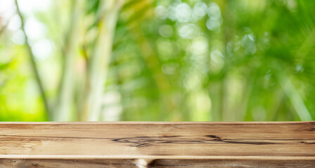 Empty wooden board or table top and blurred green bamboo culms. Place for your product display.