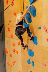 close up at the climbing wall young girl goes down the safety rope, the coach insures against...