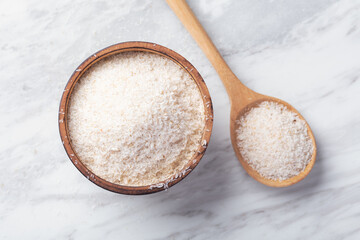 Psyllium husk in wood bowl with spoon on white marble table