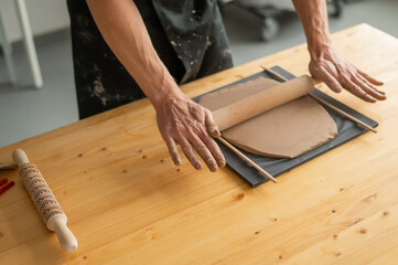 Close-up of potter's hands rolling out clay. 