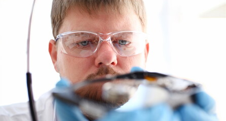 A male repairman wearing blue gloves is holding a hard drive from computer or laptop in hands....