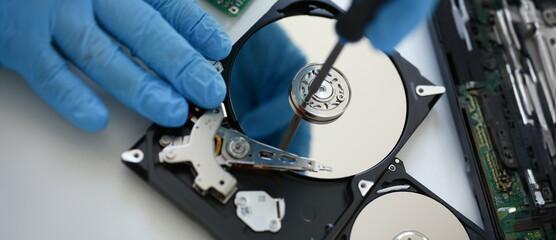 Male repairman wearing blue gloves dismantles specialized professional screwdriver hard drive....