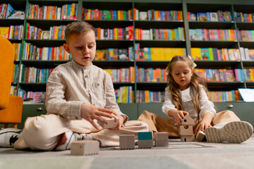 close up in a bookstore in the children area a beautiful long-haired girl and boy play with wooden...