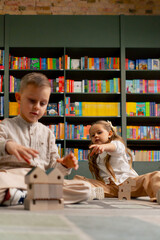 close up in a bookstore in the children area a beautiful long-haired girl and boy play with wooden toys