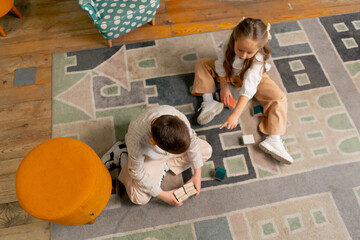 top shot in a bookstore in the children area a beautiful long-haired girl and boy play with wooden...