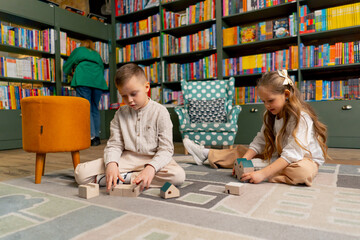 in a bookstore in the children area a beautiful long-haired girl and boy play with wooden toys