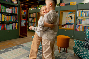 in a bookstore in the children area beautiful girl and a boy peacefully share a book