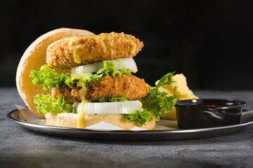 Double fish burger with potato salad on a metal plate