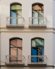 Obraz premium Colorful windows and white balconies on a residential building in Malaga, Andalusia, southern Spain.