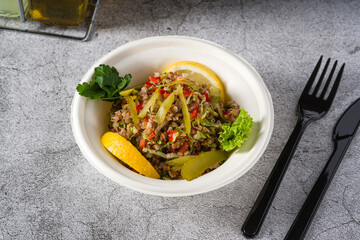 Quinoa salad on a white styrofoam plate on a stone table