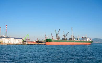 Loading onto bulk carrier ship at commercial port on a sunny day