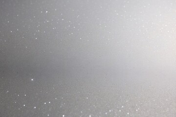 Silver sparkle background with areas of bokeh effect, creating a blurred glitter texture
