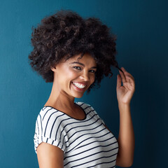 Woman, portrait and pull curly hair in studio with confidence for growth, results or smile by blue background. African person, girl and model with care, happy or transformation with cosmetic for afro