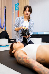 Vertical photo of a woman using an instrument to do sound therapy in a gym room. Concept of somatic...