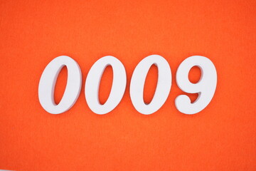 The number 0009 is made from white painted wood placed on a background of orange paper.