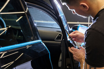 Sticker of a protective film on the headlight of a car in a car detailing studio
