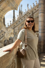 Beautiful 30s woman in sunglasses posing on Roof of Milan Cathedral Duomo di Milano, Italy. Traveling Europe in summer. Attractive blonde female is exploring city. Top tourist attraction.