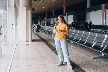 Happy Caucasian Woman waiting at Flight Gates for Plane Boarding, Uses Mobile Smartphone. 30s female Checking Trip Destination on Internet, concept of traveling. Full body