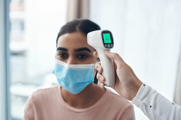 Woman, temperature and test for virus with thermometer in clinic with covid, face mask or...