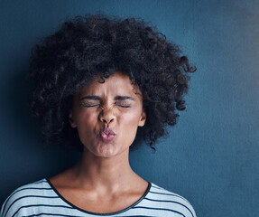 Black woman, emoji and kissing with funny face in studio for fun, relax and playful attitude on blue background. Lady, comic and goofy portrait with facial expression, crazy and personality isolated