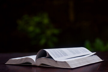 An open Christian bible on a table top with a few pages raised up