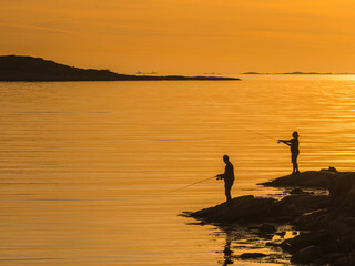 Men Fishing From a Cliff at Sunset in Swedens Serene Seascape