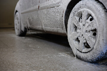 A beautiful foam-covered car sits in a car wash. Bottom view of a car treated with foam to remove...