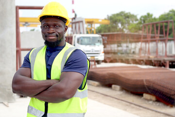 Portrait of happy smiling African engineer worker with safety vest and helmet standing with arms...