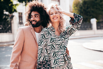 Beautiful fashion woman and her handsome elegant boyfriend in beige suit. Sexy blond model in summer suit clothes. Fashionable smiling couple posing in street Europe. Brutal man and female outdoors