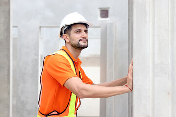 Happy worker engineer with safety vest and helmet inspecting working area at construction site....