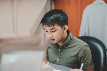Fototapeta premium Asian person working on a computer at the office
