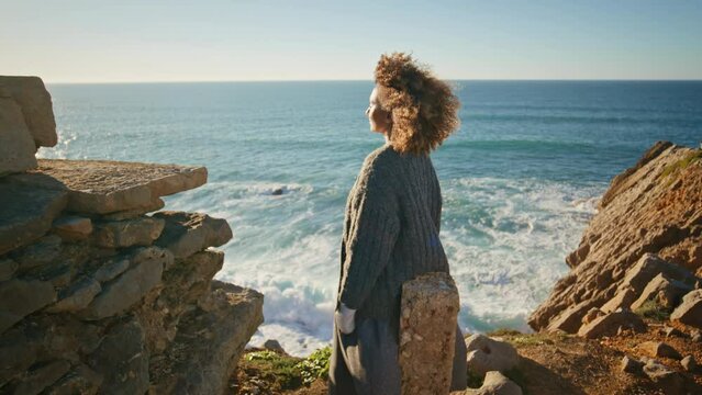 Curly woman contemplating ocean at windy coast zoom on. Girl watching sea nature