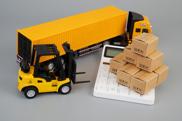Container carrier truck, calculator  and forklift truck with many carton boxes on grey background....