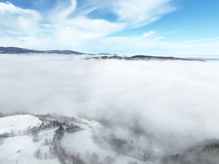 the landscape of a mountainous valley in winter, with low lying clouds covering the hills