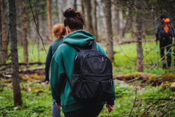 A woman carrying a backpack strolls through the wooded forest