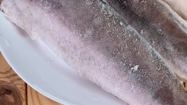 Raw frozen fillets of hake in ice glaze on plate