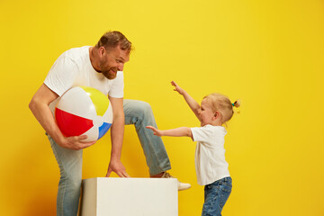 Family fun time. Delighted father and his young son enjoying playful moment with beach ball against...